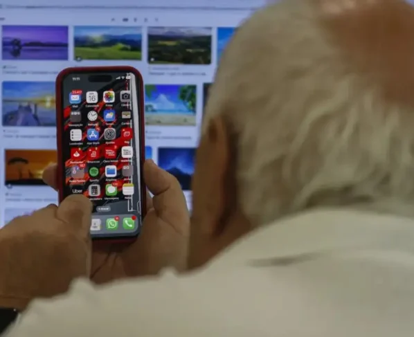 Imagem mostra idoso utilizando telefone celular